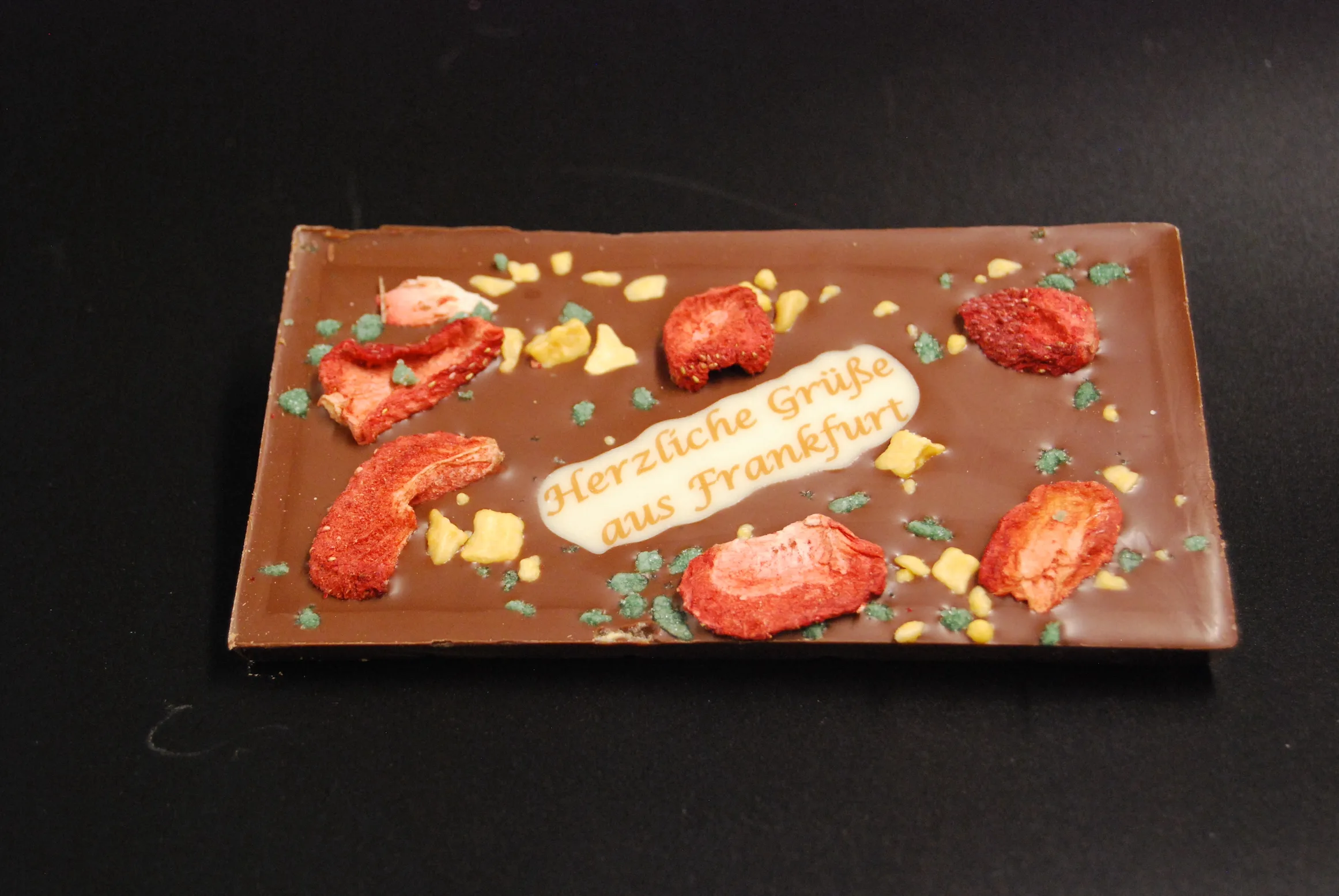 SMS-Tafel "Gruß aus Frankfurt" – handgemachte Frankfurter Schokoladentafel aus Costa-Rica-Vollmilchschokolade mit 40 % Kakao, verziert mit Minze, Erdbeeren und Passionsfrucht-Crispy; ideales Geschenk aus Frankfurt
