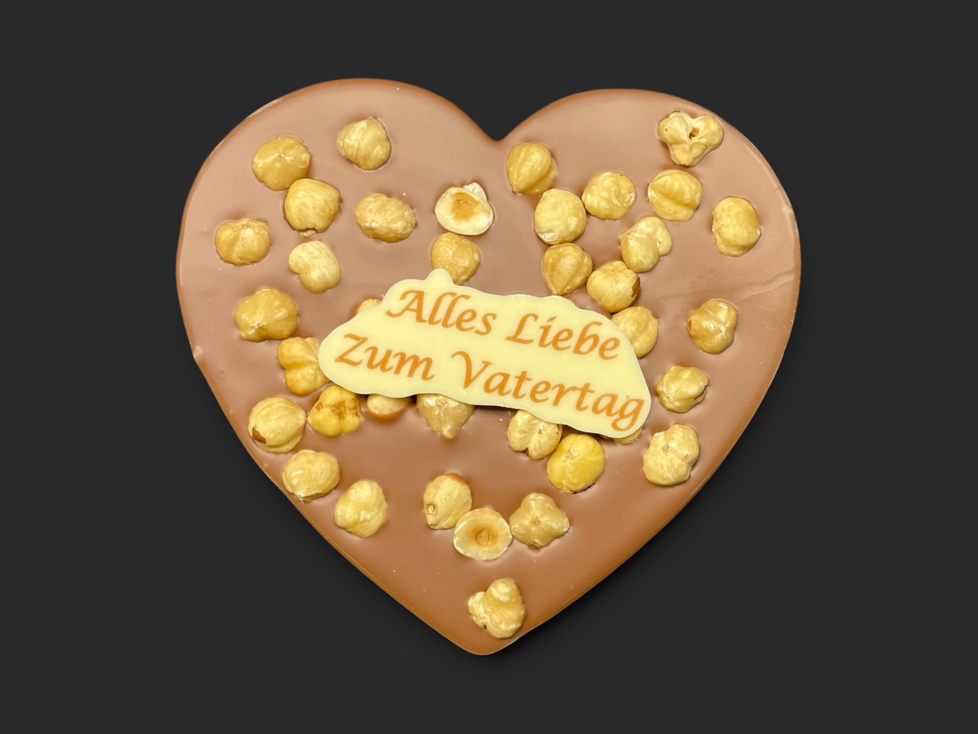 Schokoladenherz aus Vollmilchschokolade (40 % Kakao), mit Aufschrift „Schokoherz flach Vatertag Haselnüsse“
