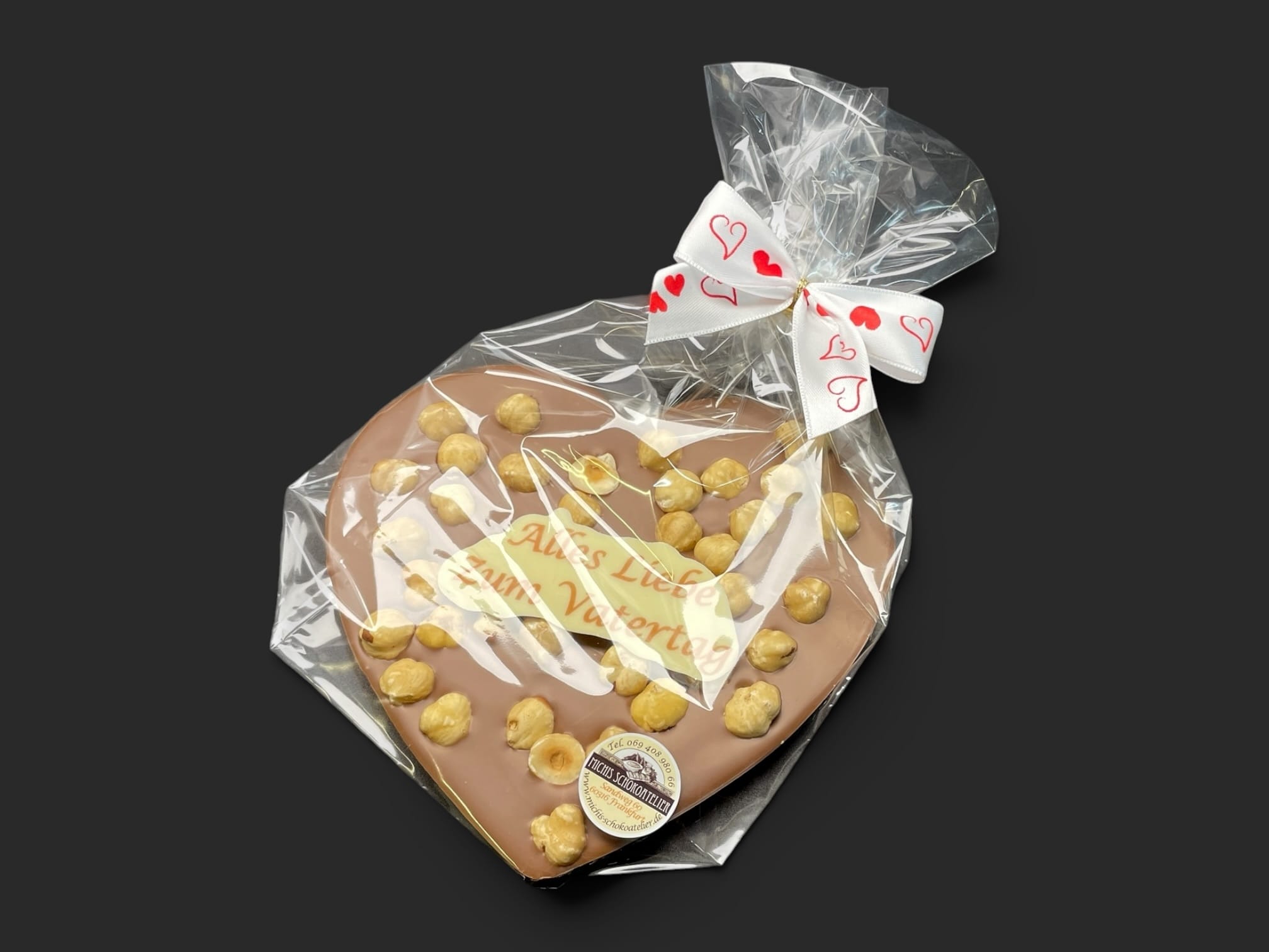 Schokoladenherz aus Vollmilchschokolade (40 % Kakao), mit Aufschrift „Schokoherz flach Vatertag Haselnüsse“, in Geschenkverpackung