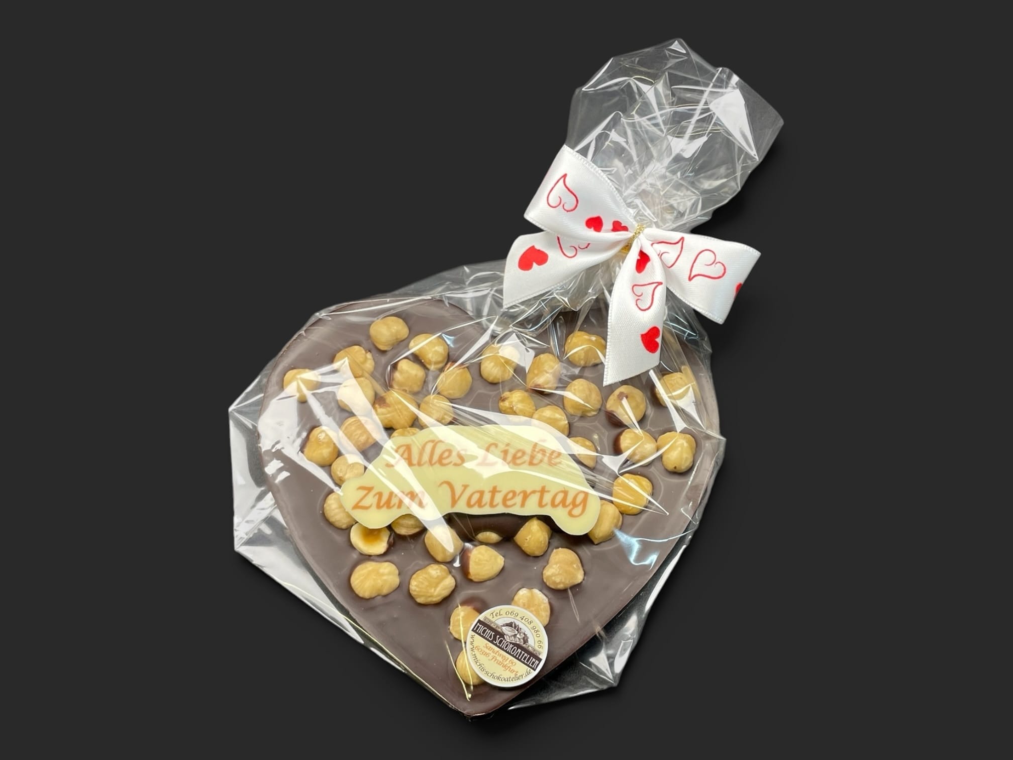 Schokoladenherz aus Zartbitterschokolade (65 % Kakao), mit Aufschrift „Schokoherz flach Vatertag Haselnüsse“, in Geschenkverpackung