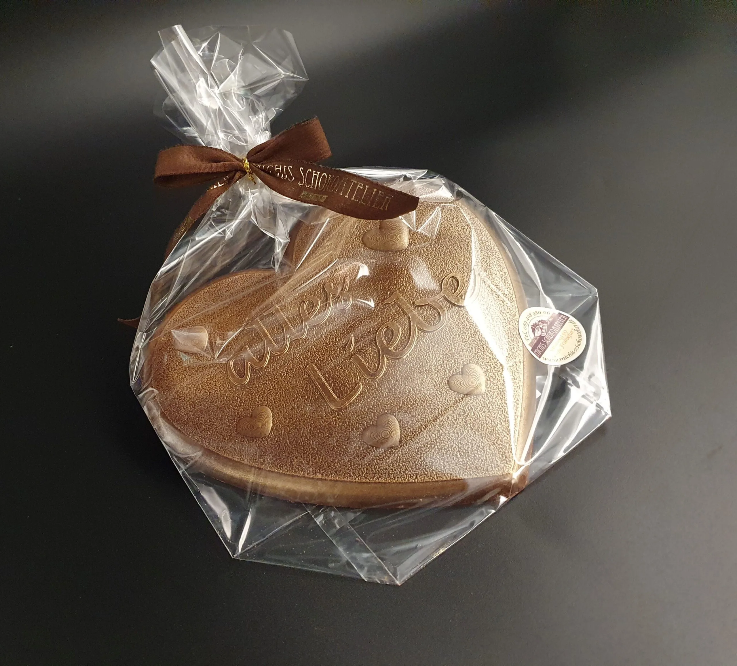 Heart made of dark chocolate with "all my love" lettering in bronze-colored food coloring, packaged