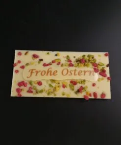 Mini Ostertafel aus weißer Schokolade mit kristallisierten Rosen, gehackten Pistazien und Aufschrift "Frohe Ostern"
